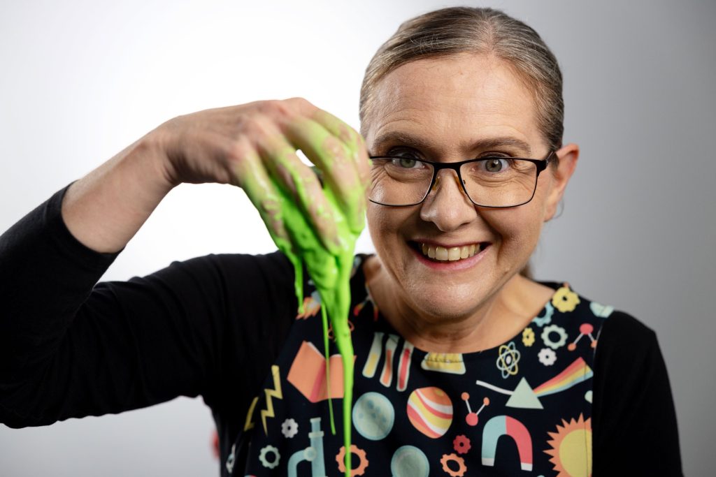 Science show presenter playing with green slime